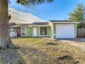 Newly painted light green house with a white garage door and a spacious lawn at 10214 Turtle Hill Ct, Tampa, FL 33615