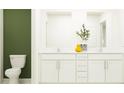 Double vanity bathroom with white cabinets and a green accent wall at 12227 Radiant Gem Trl, Parrish, FL 34219