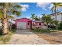 Pink house with garage and tropical landscaping at 129 Wall St, Redington Shores, FL 33708