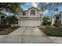 Two-story house with beige siding, attached garage, and landscaping at 5147 Sterling Manor Dr, Tampa, FL 33647