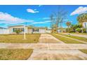 Front view of a ranch home with driveway and mature trees in the background at 5810 Town N Country Blvd, Tampa, FL 33615