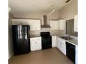 Galley kitchen with white cabinets and black appliances at 6802 Seaview Way, Tampa, FL 33615