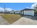 Front view of a ranch home with a white exterior and a spacious yard at 7310 Oakshire Dr, Port Richey, FL 34668