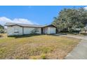 One-story home with a white exterior, attached garage, and grassy yard at 7310 Oakshire Dr, Port Richey, FL 34668