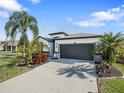 White house with dark gray garage door, landscaping, and palm trees at 12202 Legacy Bright St, Riverview, FL 33578