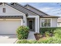 House entrance with gray siding, landscaping, and a walkway at 19724 Post Island Loop, Land O Lakes, FL 34638