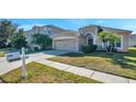 House exterior showcasing a two-car garage and landscaping at 4506 Mapletree Loop, Wesley Chapel, FL 33544