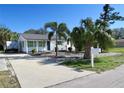 Cute white house with green shutters, palm trees, and a paved driveway at 2660 Miriam S St, Gulfport, FL 33711