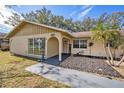 Front view of a lovely ranch home with a welcoming porch and nicely landscaped yard at 3245 Canal Pl, Land O Lakes, FL 34639