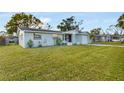 Single-story home with a green lawn, an attached garage, and mature trees in the background at 5600 Bayou Grande Ne Blvd, St Petersburg, FL 33703