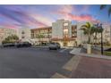 Exterior view of condo building at sunset, showcasing parking area at 7466 Bayshore Dr # 406, Treasure Island, FL 33706