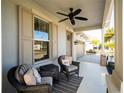 Relaxing front porch with wicker chairs and ceiling fan at 7853 Roma Dune Dr, Wesley Chapel, FL 33545