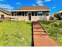 Wooden boardwalk path leading to a grassy backyard with mature trees and a glimpse of a canal at 1218 Vinetree Dr, Brandon, FL 33510