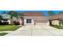 Two-story house with a two-car garage, light pink exterior, and neatly landscaped lawn at 1218 Vinetree Dr, Brandon, FL 33510