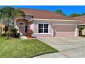 Two-story house with a two-car garage, light pink exterior, and neatly landscaped lawn at 1218 Vinetree Dr, Brandon, FL 33510