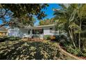 Charming light blue house with a welcoming front porch and lush landscaping at 1120 Idlewild N Dr, Dunedin, FL 34698