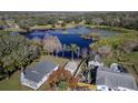 Aerial view of a house and property with a detached garage and lake access at 11416 Pine Forest Dr, New Port Richey, FL 34654