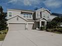 Two-story house with gray siding, three-car garage, and landscaped yard at 5709 Camila Song Ln, Tampa, FL 33625