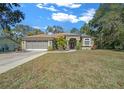 Green house with red door, two car garage, and landscaped yard at 628 Erin Way, Brooksville, FL 34601