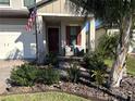 Covered porch with seating area, American flag, and nicely landscaped surroundings at 8365 Capstone Ranch Dr, New Port Richey, FL 34655
