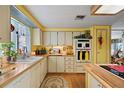 Galley kitchen with wood countertops, white cabinets, and built-in appliances at 9790 66Th N St # 130, Pinellas Park, FL 33782