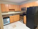 Galley kitchen with wood cabinets, appliances, and tile floor at 21026 Voyager Blvd # 6, Land O Lakes, FL 34638