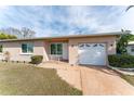 Single-story house with a beige exterior, a white door and garage, and landscaping at 1004 Orlando Ave, Bradenton, FL 34207