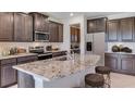 Modern kitchen with dark cabinetry, granite island, and stainless steel appliances at 10825 Patoka Ter, Parrish, FL 34219