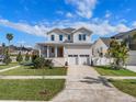 Charming two-story white home with a welcoming front porch, lush lawn, and a two-car garage at 323 Appian Ne Way, St Petersburg, FL 33704