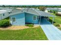 An aerial view of a light blue manufactured home with a carport and landscaping at 37622 New Horizons Blvd, Zephyrhills, FL 33541