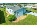 An aerial view of a light blue manufactured home with a carport and landscaping at 37622 New Horizons Blvd, Zephyrhills, FL 33541
