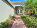 Brick walkway leading to the front entrance of a light green house at 15724 Aurora Lake Cir, Wimauma, FL 33598
