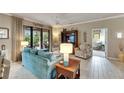Cozy living room with teal sofa and light wood floors, looking toward a second living space at 205 Silver Falls Dr, Apollo Beach, FL 33572