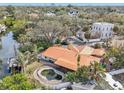 An aerial perspective of the home featuring a unique pool, lush greenery, and a serene waterfront setting at 4829 W San Miguel St, Tampa, FL 33629