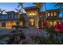 Elegant two-story home with fountain, balcony, manicured landscaping, driveway, and warm exterior lighting at 26 Sunset Bay Drive, Belleair, FL 33756