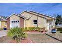 Front view of a charming yellow house with well-maintained landscaping at 37347 Derbyshire Dr, Zephyrhills, FL 33542