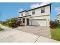Two-story house with a white facade, paver driveway, and landscaping at 4062 Cadence Loop, Land O Lakes, FL 34638