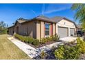 Tan house with gray two-car garage and landscaping at 13987 Weddington Ter, Hudson, FL 34669