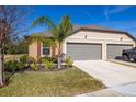 Tan house with gray two-car garage, landscaping, and a truck parked in driveway at 13987 Weddington Ter, Hudson, FL 34669