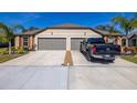 Tan house with gray three-car garage, landscaping, and a truck parked in driveway at 13987 Weddington Ter. Ter, Hudson, FL 34669