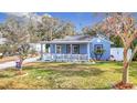 Quaint blue house with a porch, white fence, and manicured lawn at 1447 Santa Anna Dr, Dunedin, FL 34698
