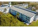 Aerial view of the condo building with a lush green lawn, mature trees, and ample parking space at 2468 Florentine Way # 52, Clearwater, FL 33763