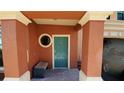 Building entryway featuring a teal door, stone walkway, and a bench at 2757 Via Cipriani # 1114A, Clearwater, FL 33764
