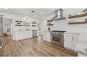 Bright kitchen with stainless steel appliances, white cabinets, and wood floating shelves at 502 Althea Rd, Belleair, FL 33756