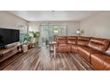 Living room featuring a brown leather sectional and wood-look floors at 8729 Sheldon Creek Blvd, Tampa, FL 33615