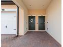 Front entry of townhouses featuring two dark green doors and brick pavers at 10043 Crooked Creek Dr # 202, Venice, FL 34293
