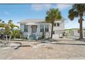 Charming coastal home with light exterior, lush landscaping, and welcoming front porch at 14157 N Bayshore Dr, Madeira Beach, FL 33708