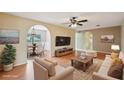 Staged living room with hardwood floors, ceiling fan, arched doorways, and open dining area, promoting comfortable living at 10704 Mira Vista Dr, Port Richey, FL 34668