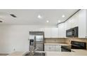 White kitchen cabinets with stainless steel refrigerator and black oven at 15107 Morning Dr, Lutz, FL 33559