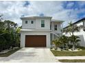 Two-story house with white exterior, brown garage door, and landscaping at 1840 Douglas Ave, Dunedin, FL 34698